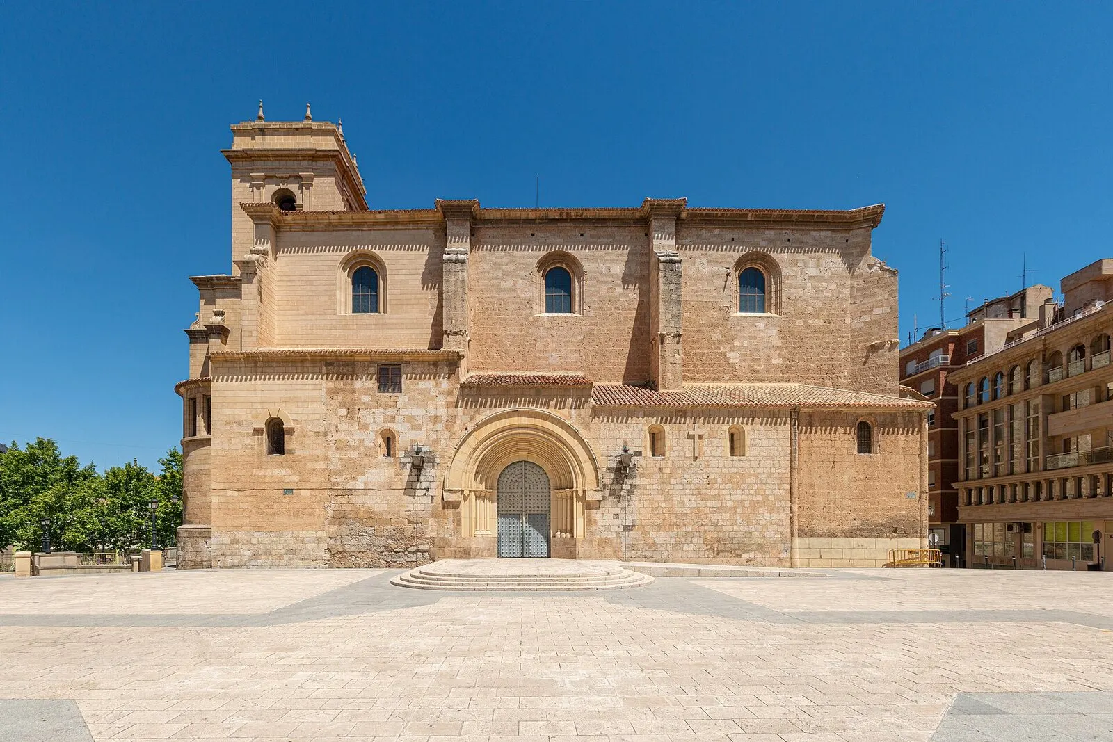 Fachada sur de la catedral de San Juan de Albacete, de piedra dorada, ante una plaza despejada y cielo azul