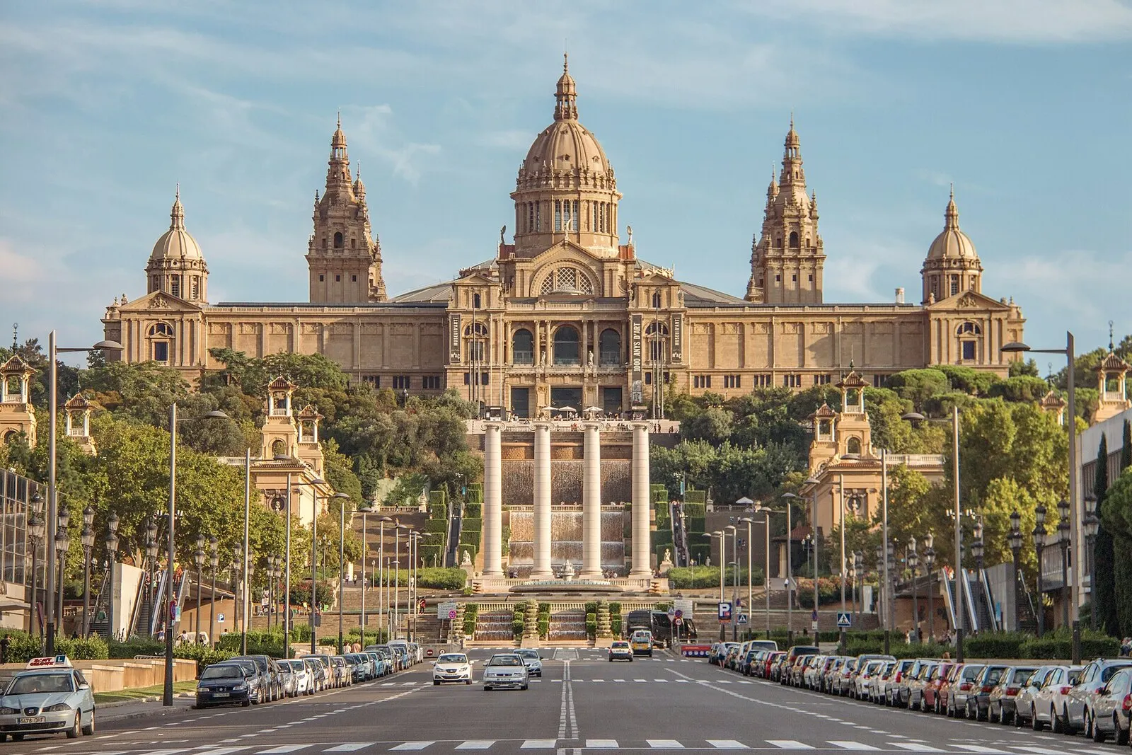 El Palau Nacional de Montjuïc, con su cúpula y sus torres, visto desde la avenida con las cuatro columnas delante