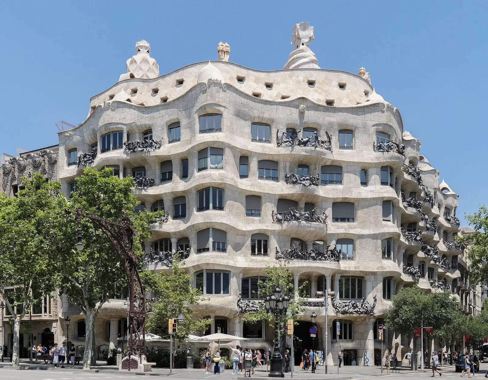 Fachada ondulada de piedra de La Pedrera, con sus balcones de hierro forjado, en el paseo de Gràcia bajo un cielo azul
