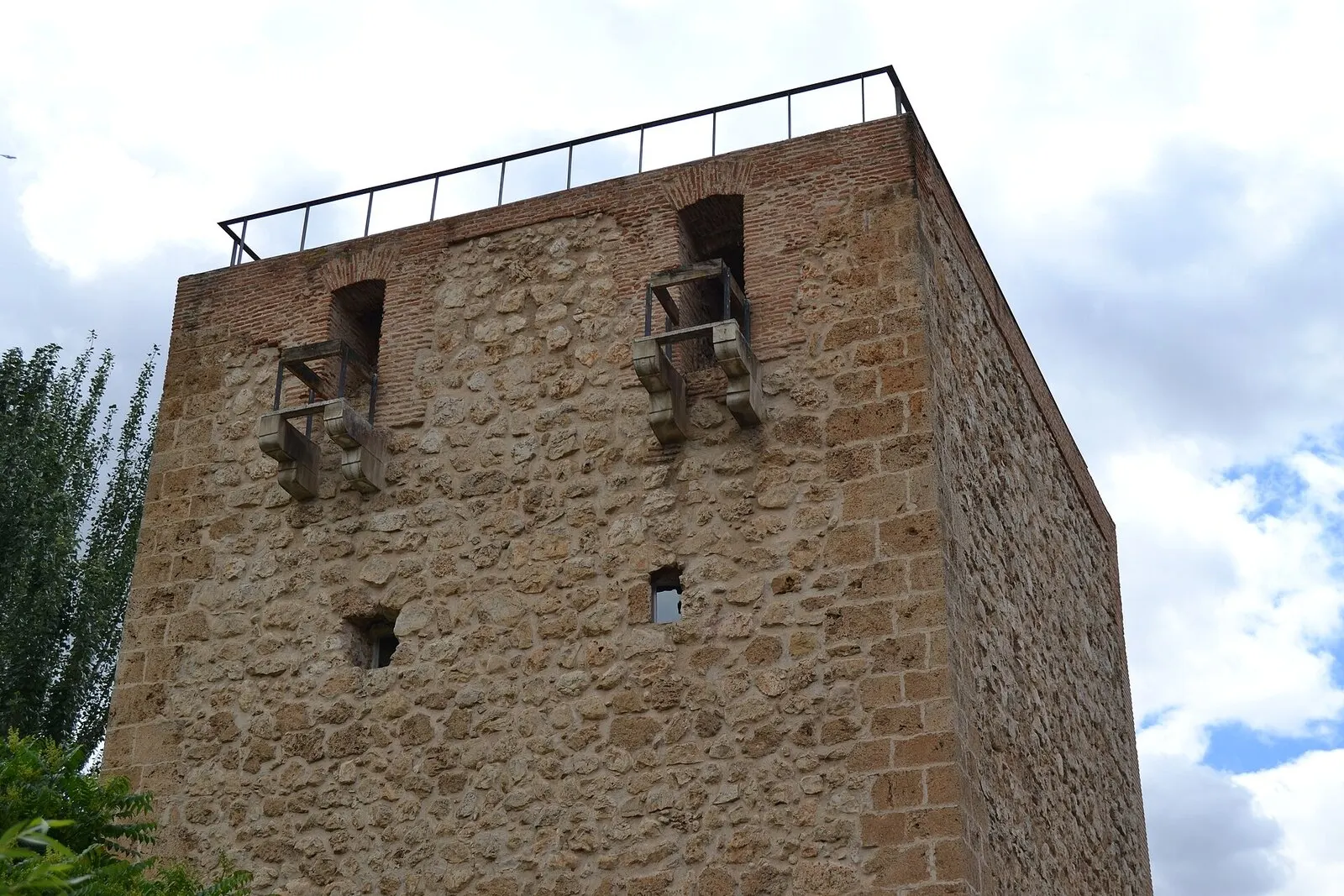El torreón medieval del Alamín, de mampostería y ladrillo, con sus matacanes bajo un cielo de nubes