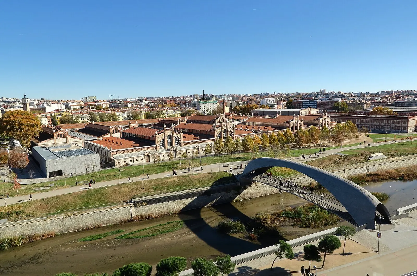 El puente de Matadero sobre el Manzanares, con las naves de ladrillo de Matadero detrás, bajo un cielo azul
