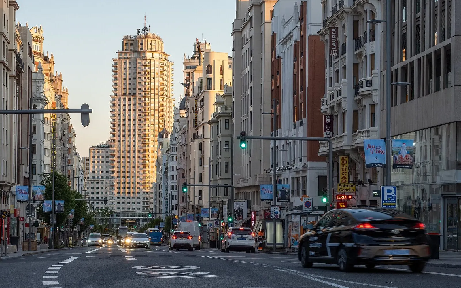 La Gran Vía de Madrid de día, con el Edificio España al fondo y coches circulando entre las fachadas