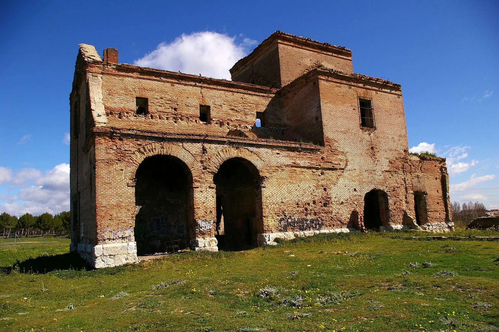 Ruinas de ladrillo de la iglesia de San Pedro sobre la pradera del parque de Polvoranca, con cielo azul