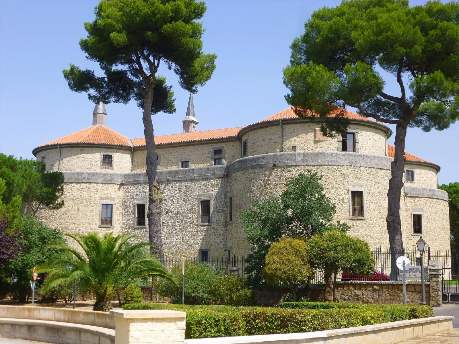 El castillo de Villaviciosa de Odón, de torres redondas y tejados rojos, entre pinos y jardines