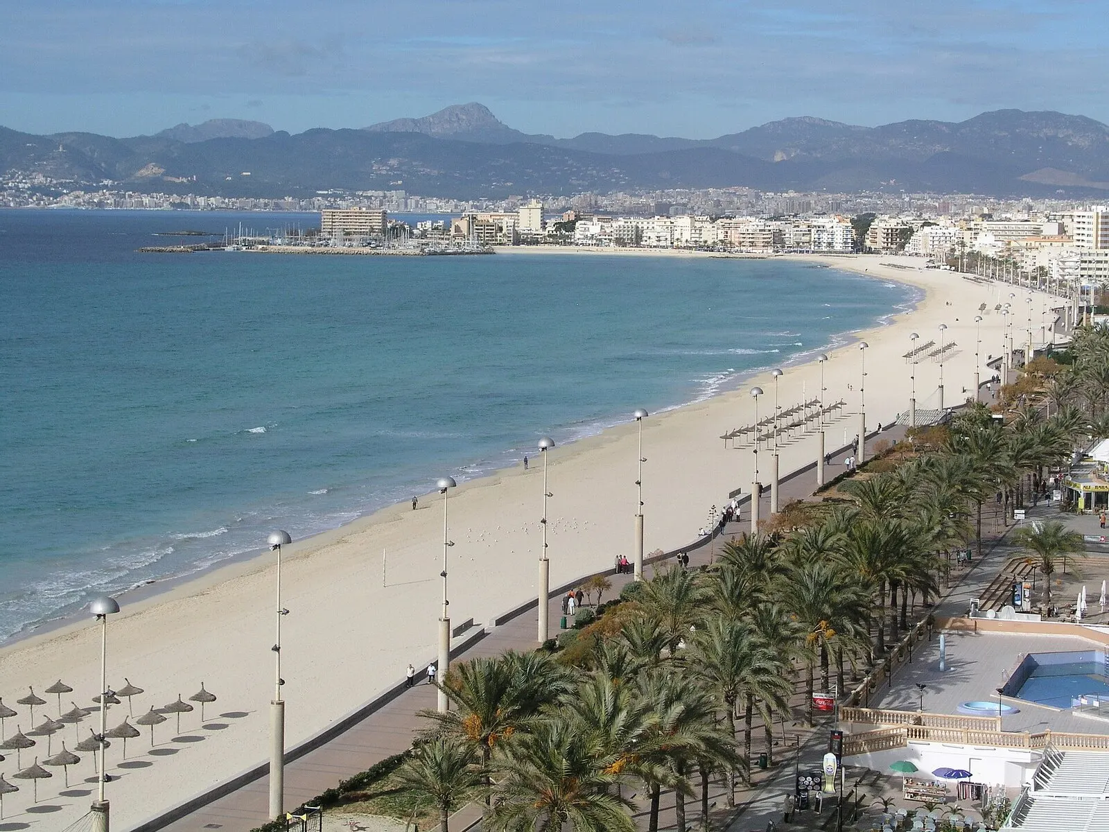La larga playa de Palma y su paseo con palmeras, vista desde lo alto, con Can Pastilla y la sierra al fondo
