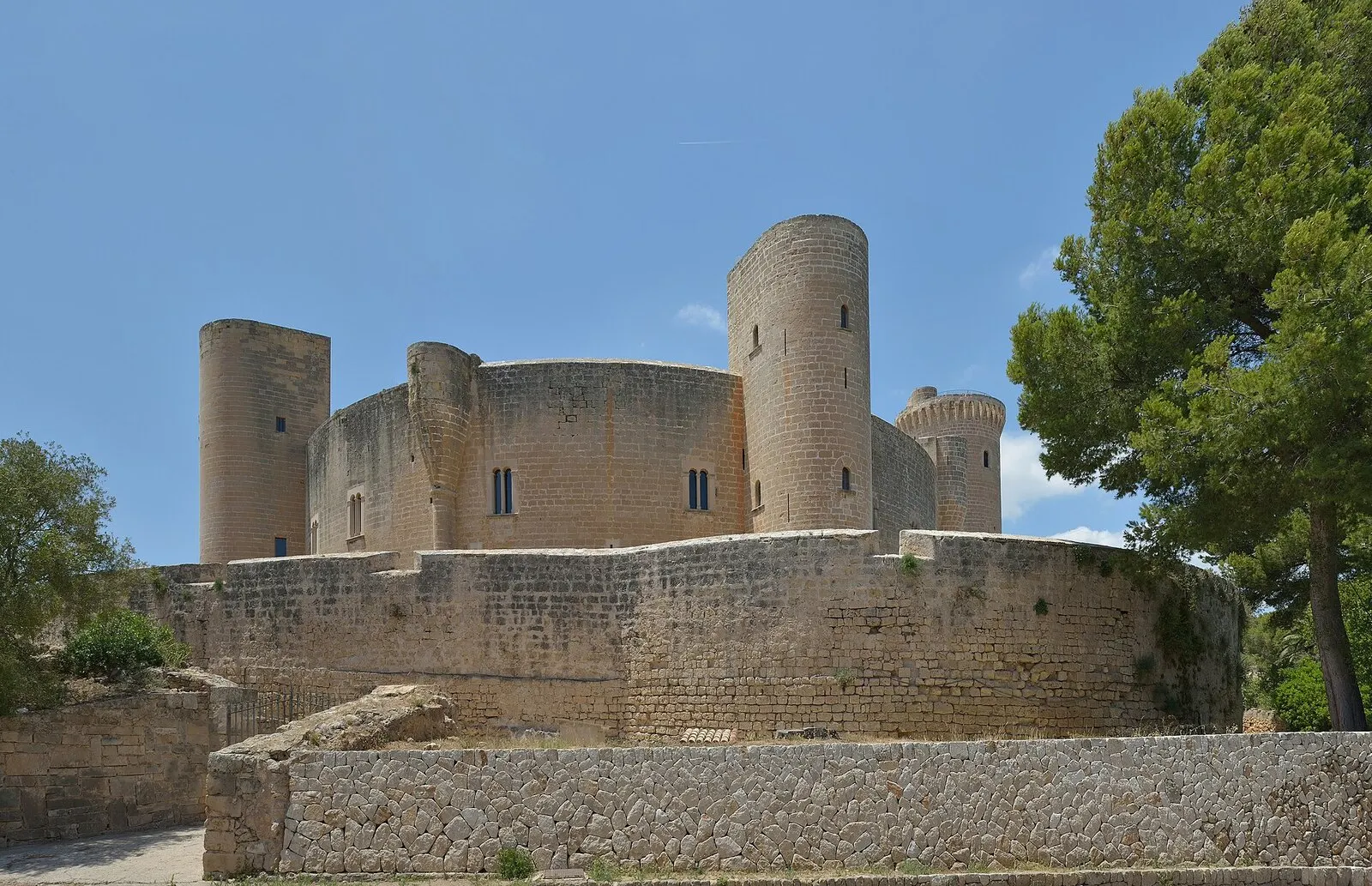 El castillo de Bellver, de planta circular y torres redondas, rodeado de pinos bajo un cielo azul