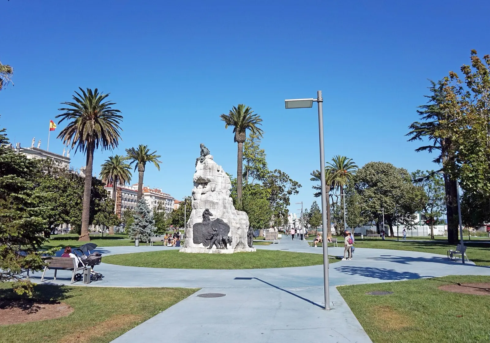 Monumento a Pereda entre palmeras y césped en los jardines de Pereda, en un día soleado