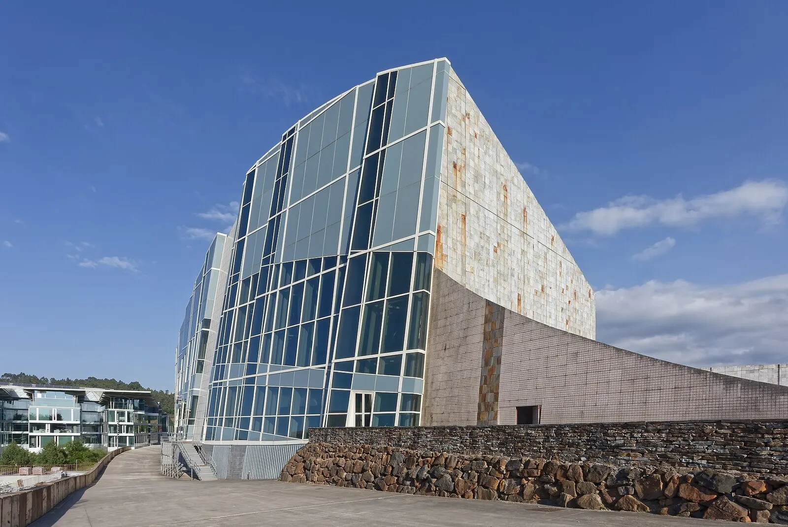 La Biblioteca de Galicia en la Cidade da Cultura, con su fachada de vidrio y piedra bajo un cielo azul