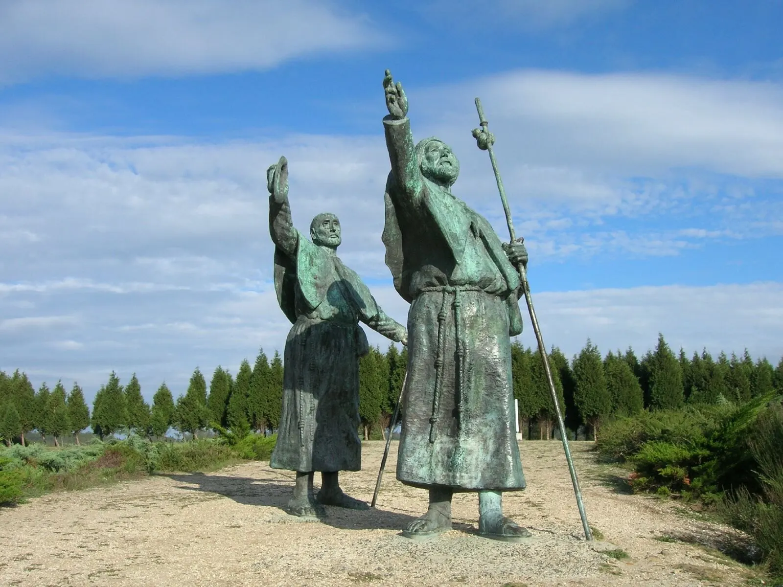Las dos estatuas de bronce de peregrinos que señalan hacia Santiago en el Monte do Gozo, con cielo azul