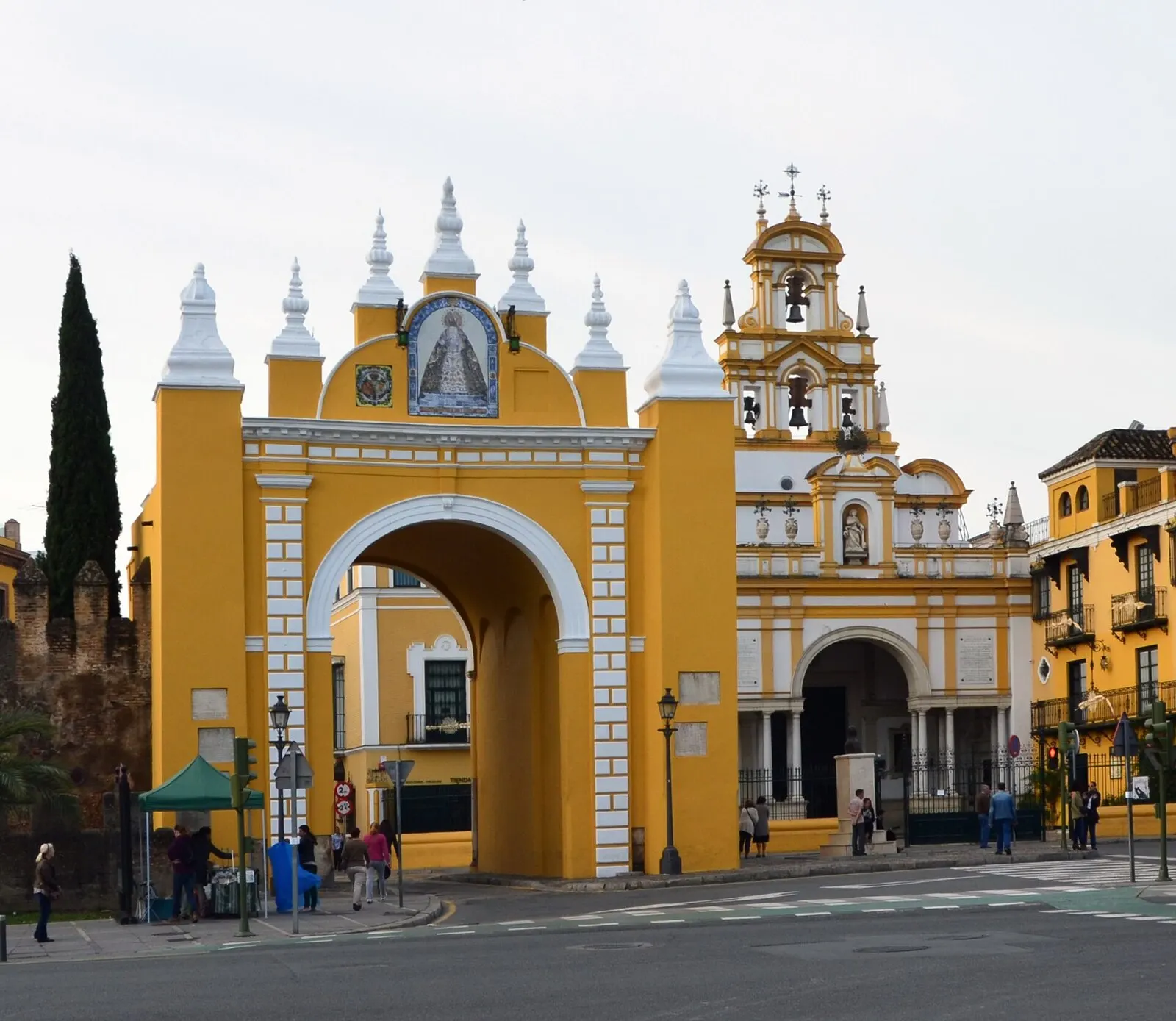 El arco amarillo y blanco de la Puerta de la Macarena, con la espadaña de la basílica a la derecha