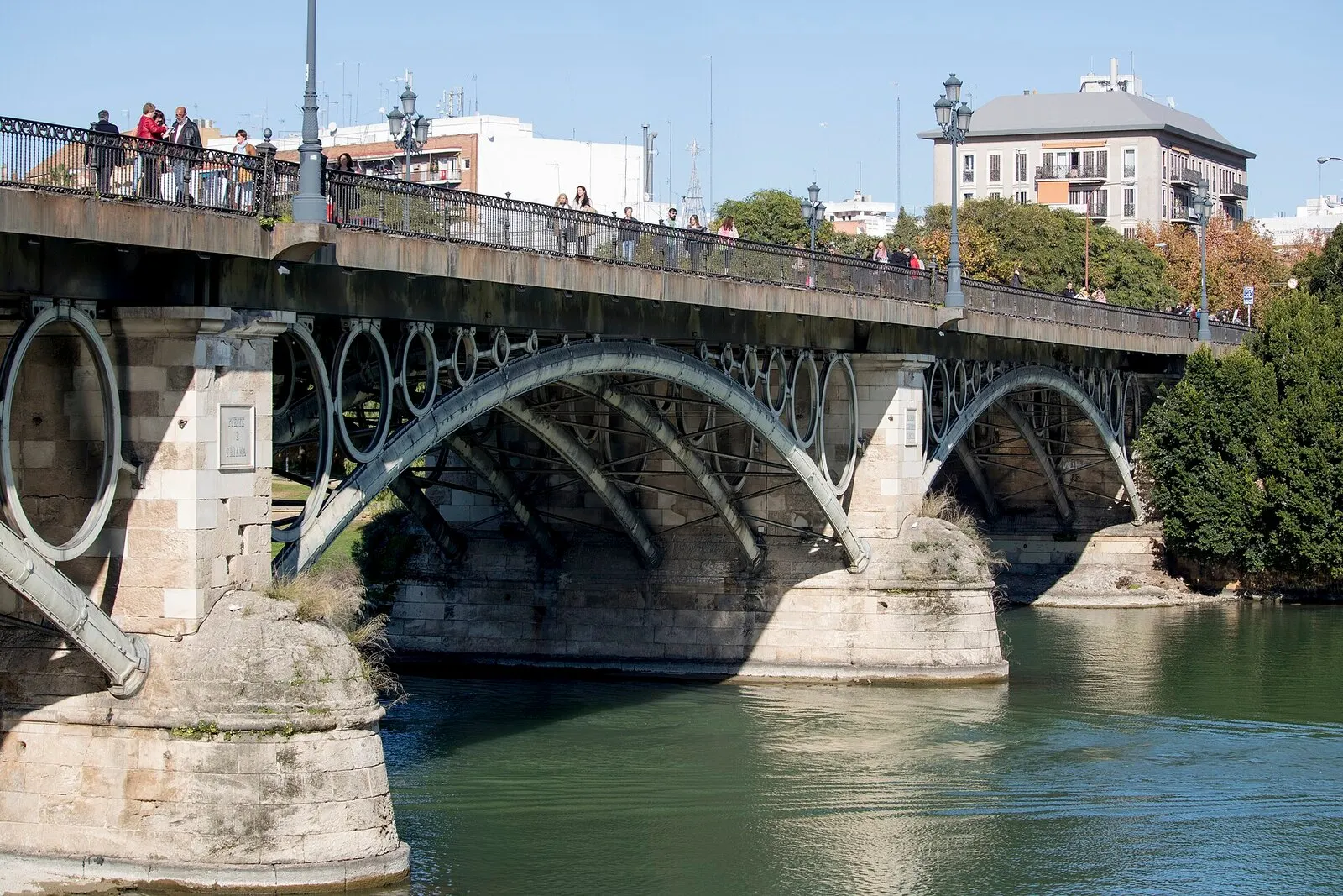 Los arcos de hierro del puente de Triana sobre el Guadalquivir, vistos desde la orilla en un día claro
