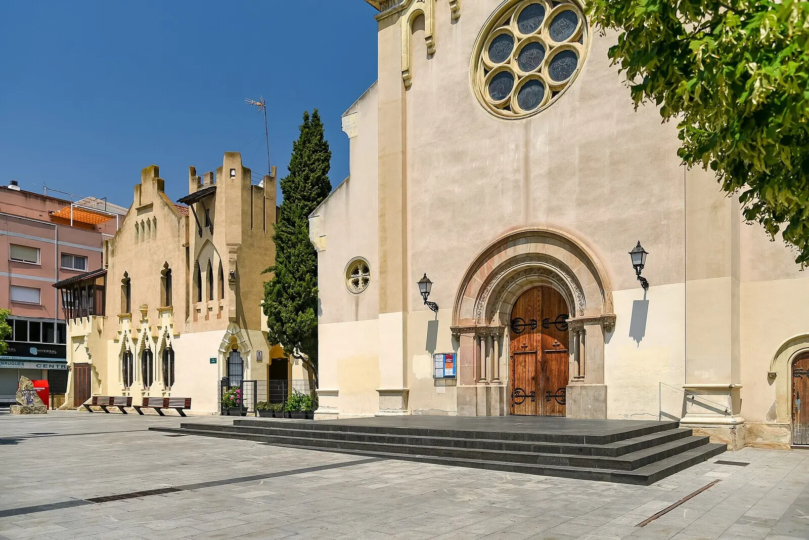 La fachada de la iglesia de Sant Martí de Cerdanyola, con su rosetón y portada, junto a una plaza soleada